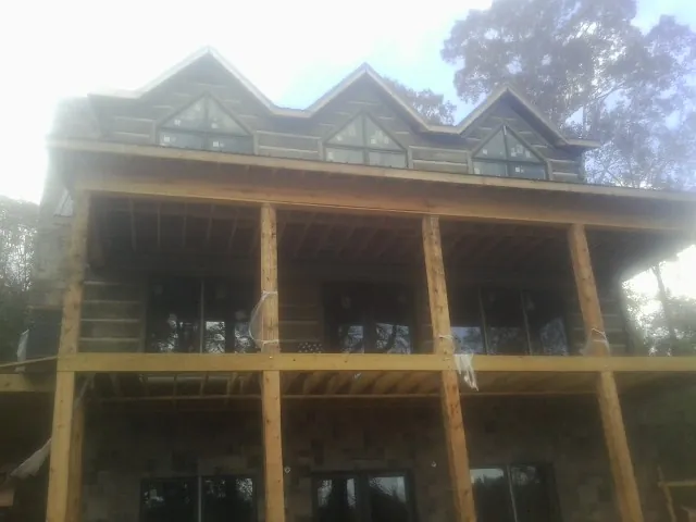 Dormers and porch framing on a large log home under construction — Roof Coating work by our crew in Slinger