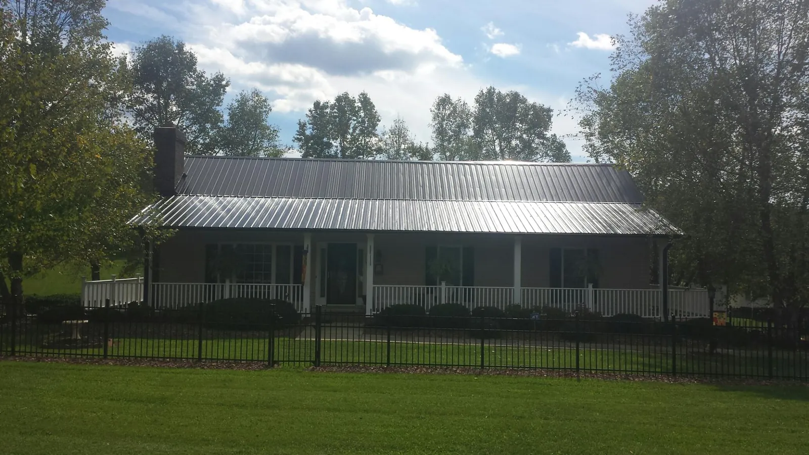 Gray metal roof on a brick ranch with a full width front porch — Gutter Guard Installation work by our crew in Slinger