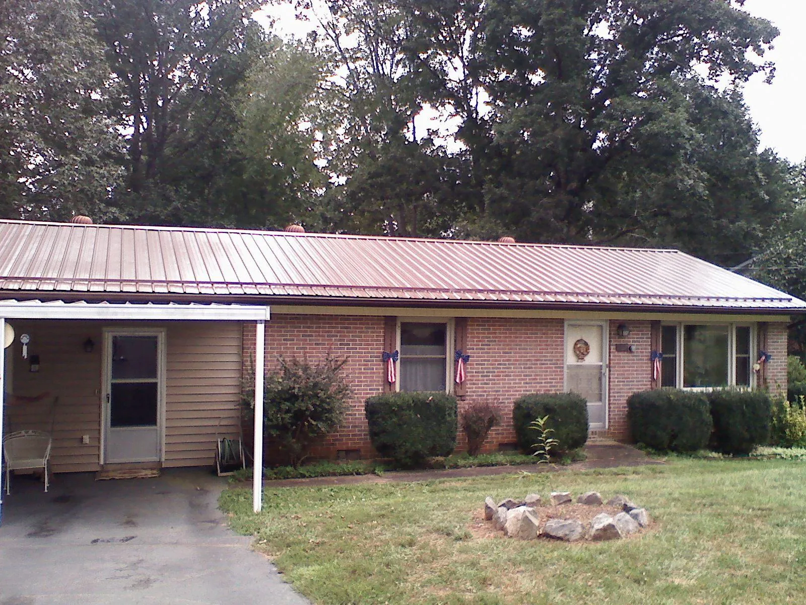 Bronze metal roof and carport on a brick ranch home — Roof Repair work by our crew in Slinger